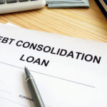 Debt consolidation loan application form on a wooden desk with a pen, calculator, and notebook nearby.
