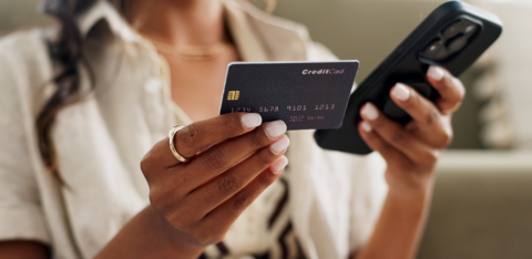 Woman holding a credit card in one hand and a smartphone in the other