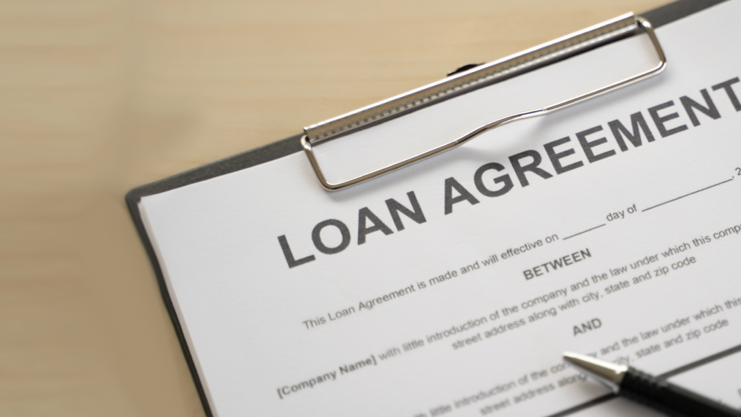 Close-up of a loan agreement form on a clipboard with a pen nearby.